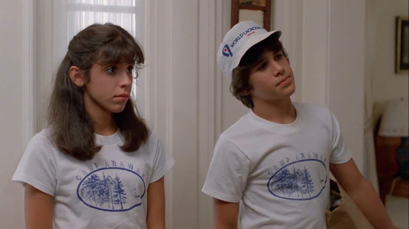 Still from Sleepaway Camp (1983). Angela and Ricky stand side by side wearing their Camp Arawak t-shirts. Both look somewhat skeptical.